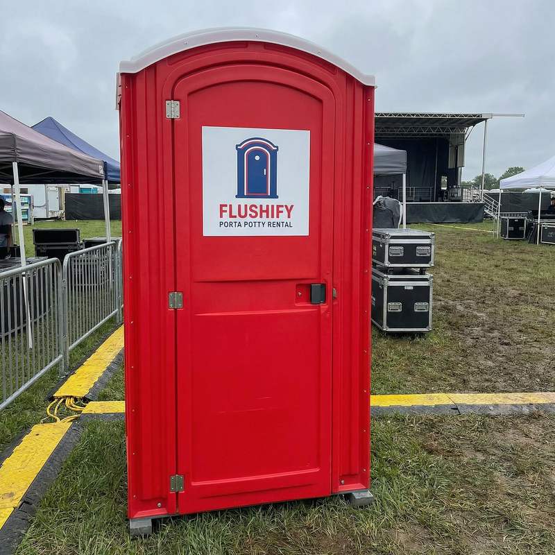 Red portable toilet behind a concert stage