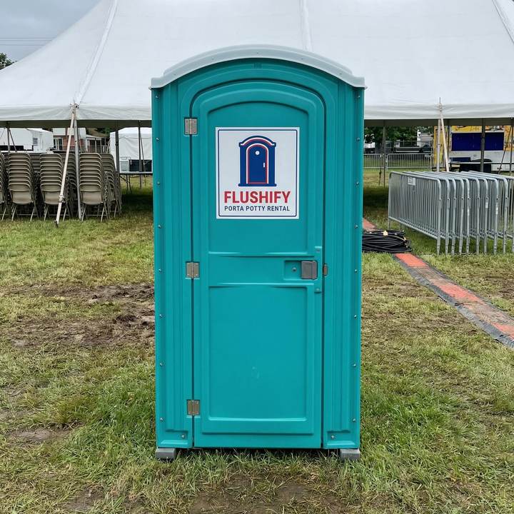 Teal portable toilet beside an event tent