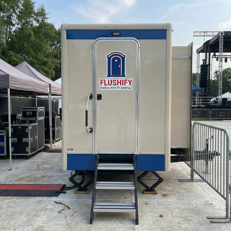 Beige restroom trailer parked at an outdoor event
